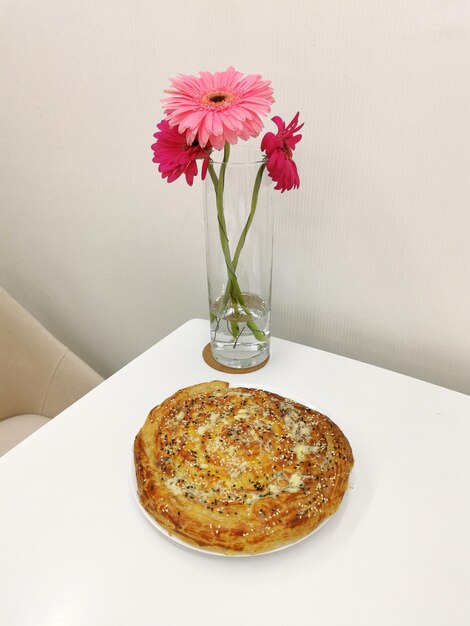 Homemade pie and colorful bouquet of gerberas on a white table