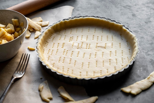 Homemade pie crust in pie plate. Cooking apple pie, dark background.