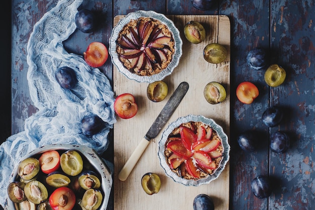 Homemade pie of fresh organic plums on wooden board and rustic table Seasonal healthy vegeterian food autumn dessert top view selective focus