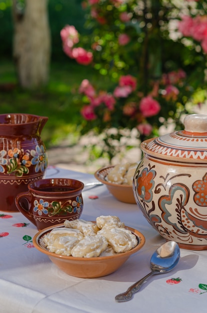 Homemade pierogi in clay ethnic Ukrainian dishes on a table in the summer garden.