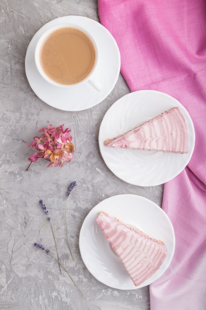 Homemade pink cheesecake with cup of coffee on a gray concrete surface. top view.