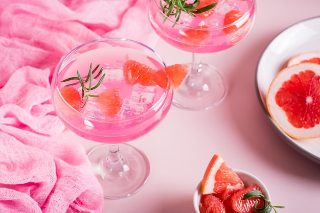 Homemade pink cocktail with ice and rosemary in glasses on the table