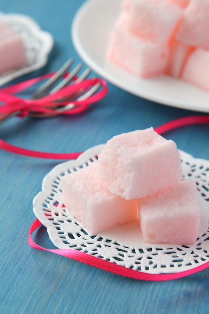 Homemade pink marshmallows on blue wooden background, selective focus