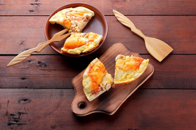 Homemade pizza on clay plate and cutting board Pizza and wooden cutlery on brown background