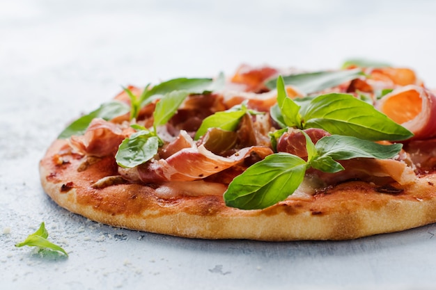 Homemade pizza with jamon, mozzarella and fresh basil leaves  