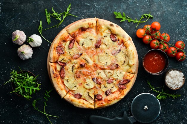 Homemade Pizza with sausages mushrooms and cheese On a black stone background Free space for text