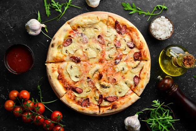 Homemade Pizza with sausages mushrooms and cheese On a black stone background Free space for text