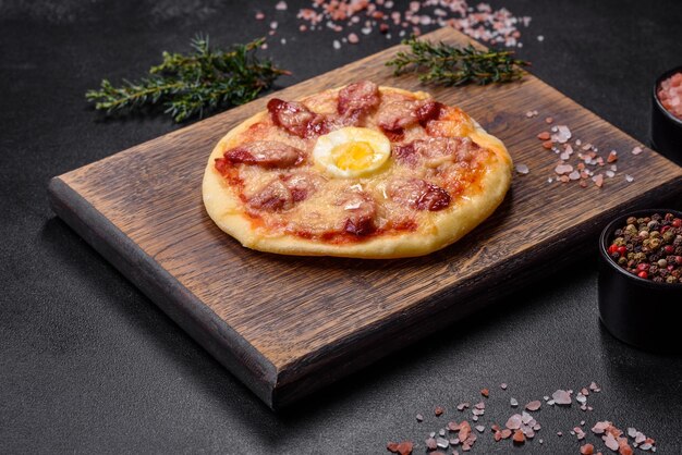 木製のまな板にソーセージ トマト チーズ スパイスとハーブの自家製ピザ