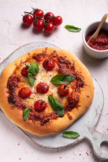 Homemade pizza with tomato and basil on a white board