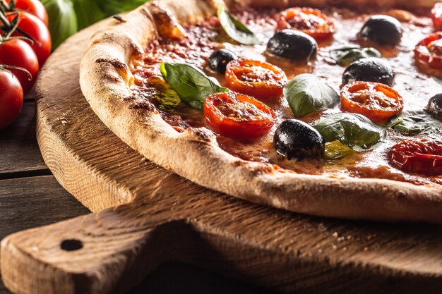 Homemade pizza with tomatoes mozzarella cheese olives and basil