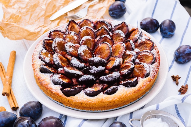 Homemade plum pie on the wooden surface