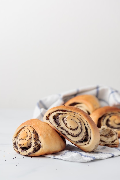 Homemade poppy seed roll buns on a white table