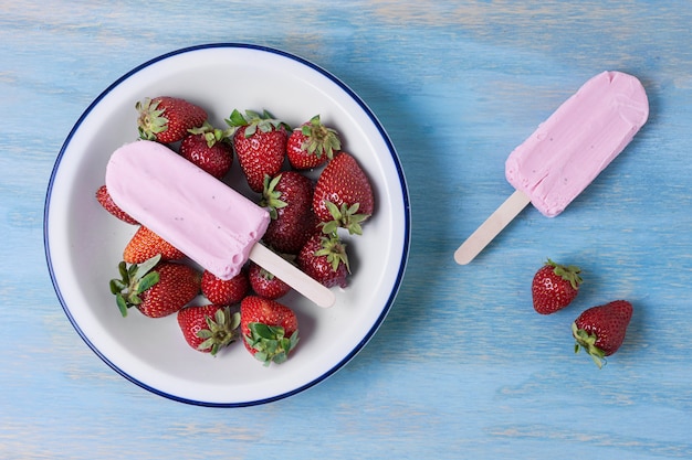 Homemade popsicle ice cream and bowl with strawberries