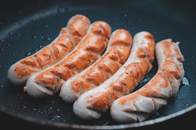 Photo homemade pork sausage grilled with oil on black pan