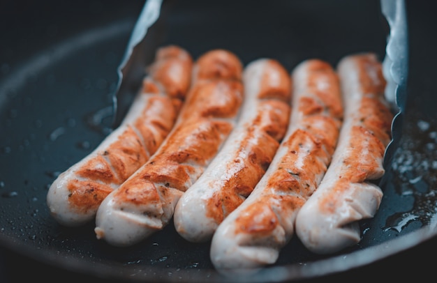 Photo homemade pork sausage grilled with oil on black pan