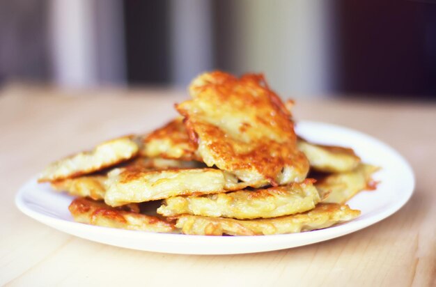 Homemade potato pancakes in a white plate on a wooden table