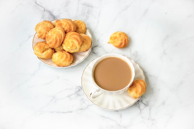 Photo homemade profiteroles stuffed with whipped cream and milk tea on a marble light background view from above