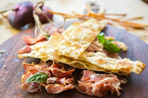 Homemade prosciutto and basil on a wooden board