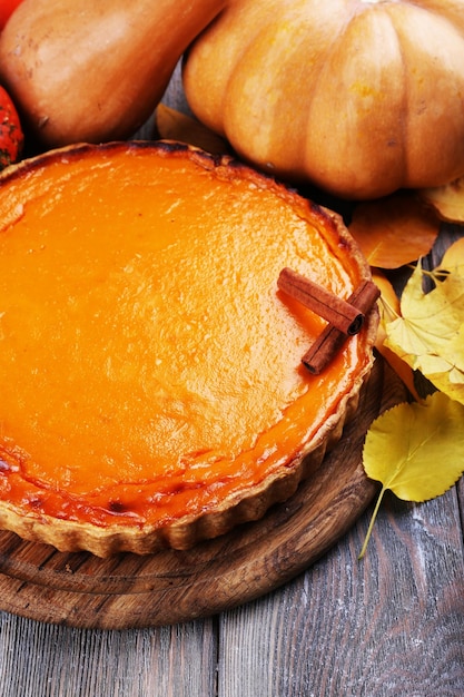 Homemade pumpkin pie on cutting board on wooden background