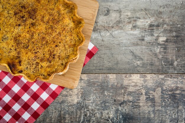 Homemade pumpkin pie on wooden background.