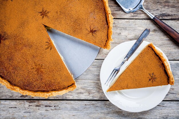 Homemade pumpkin pie on wooden rustic background top view