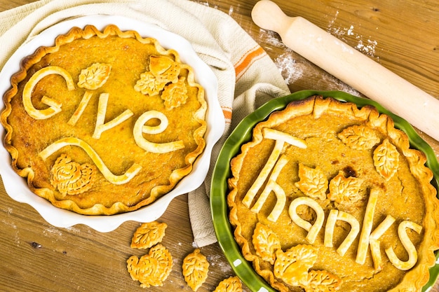 Homemade pumpkin pies with give thanks sign and autumn stamped leafs