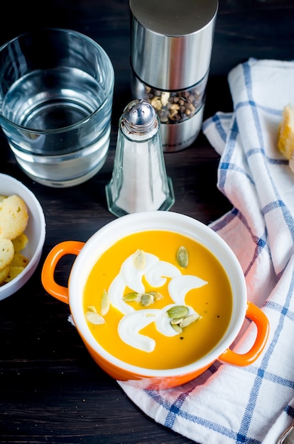 Homemade pumpkin soup in ceramic bowl with seeds, sour cream