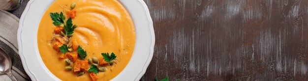 Homemade pumpkin soup in white ceramic dish on an old concrete or stone background. Selective focus. Top view. Copy space