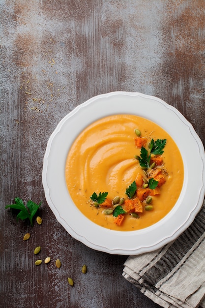 Homemade pumpkin soup in white ceramic dish on an old concrete or stone