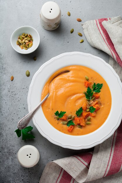 Homemade pumpkin soup in white ceramic dish on old gray concrete or stone