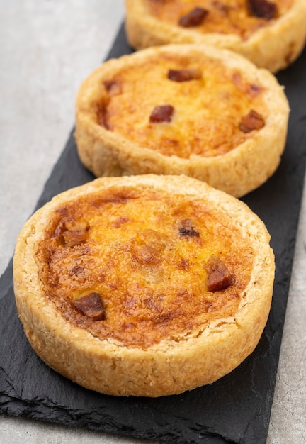 Photo homemade quiche lorraine over stone board. traditional bacon and cheese french pie.