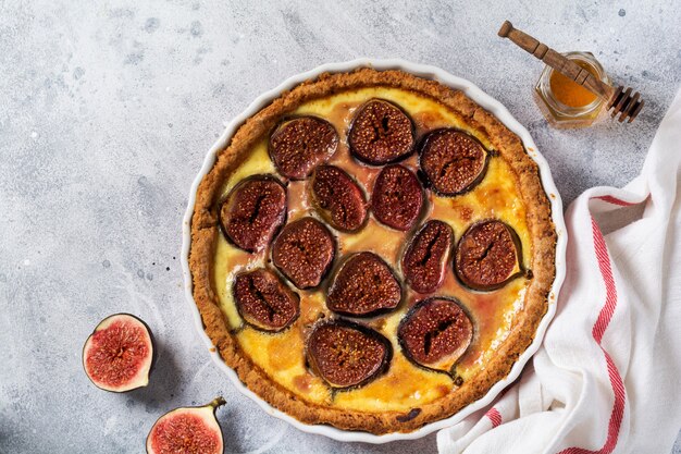 Homemade quiche tart with figs, cream cheese and honey on light wooden background. Vintage style. Top view