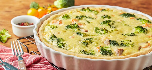 Homemade quiche with red fish, salmon, broccoli and cheese on wooden background