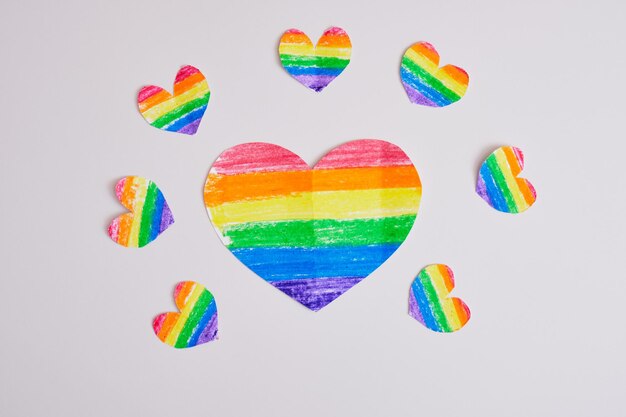 Homemade rainbow hearts on a gray background, drawn and cut hearts in the colors of the lgbt pride community flag, one heart is large and somewhat smaller