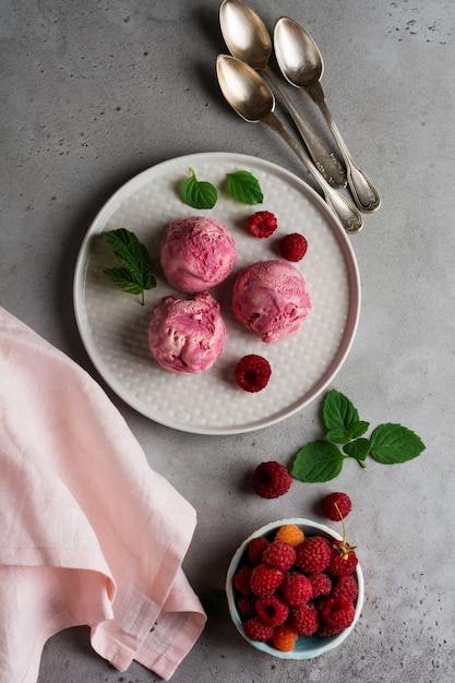 Homemade raspberry ice cream with fresh berries on gray ceramic plate. Top view.