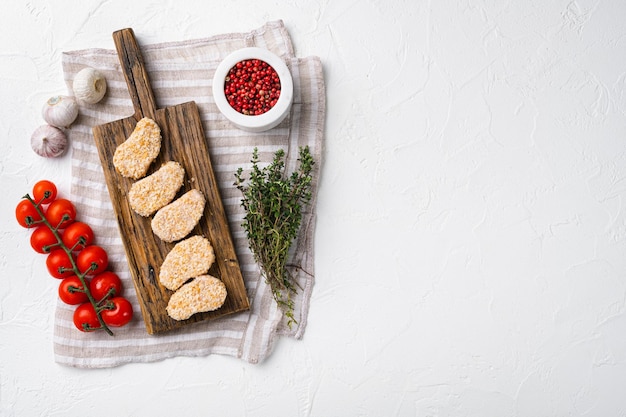 Homemade Raw Breaded Chicken Nuggets set on white stone table background top view flat lay with copy space for text