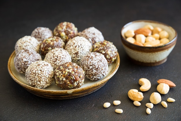 Homemade raw candy energy balls with almond, cashews, peanut butter and hazelnuts on the plate on the dark background close up. Organic snack. Vegetarian food.