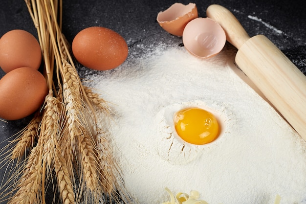 Homemade raw noodles made from flour, egg on wooden bowl on black