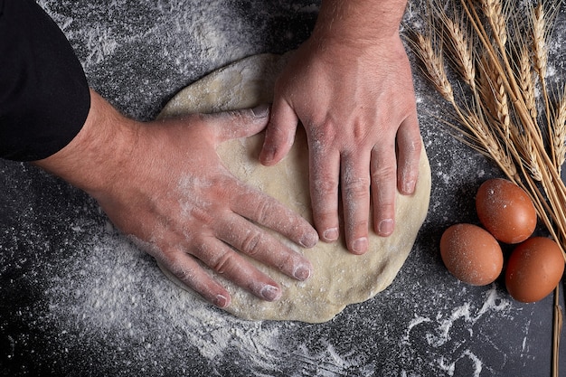 Homemade raw noodles made from flour, egg on wooden bowl on black