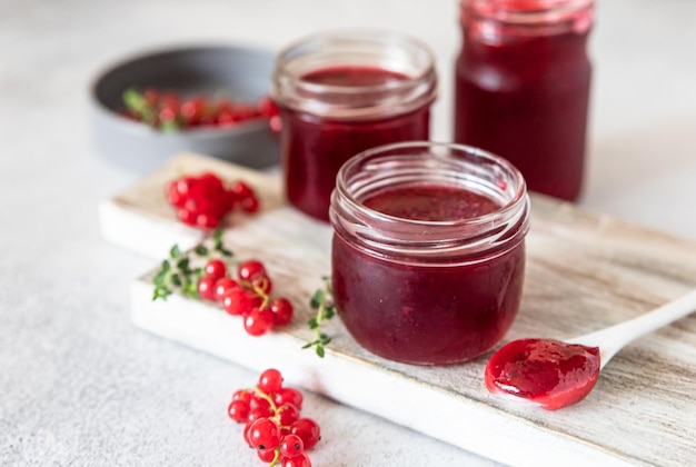 Homemade red currant jam or jelly in glass jars and red currants berries