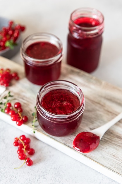 Homemade red currant jam or jelly in glass jars and red
currants fresh berries on wooden board