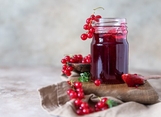 Homemade red currant jam or jelly in glass jars and red currants fresh berries.