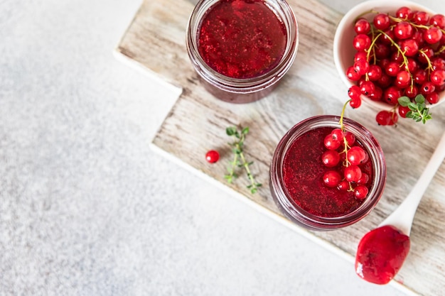 Homemade red currant jam or jelly in glass jars and red currants fresh berries