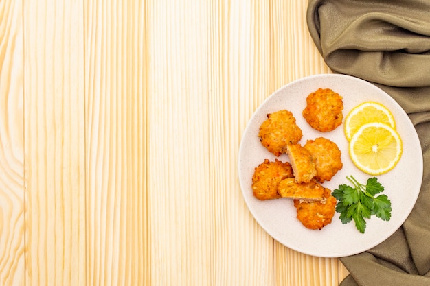 Homemade red fish cakes with lemon and parsley in ceramic plate. with fabric drapery on wooden surface, top view, copy space