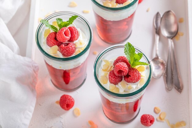 Homemade red jelly with raw raspberries and whipped cream