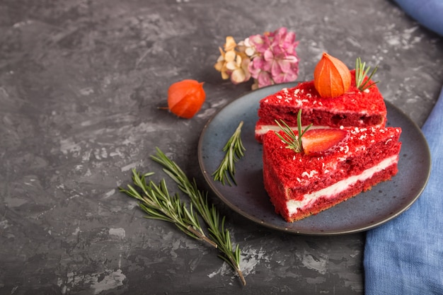Домашний красный бархатный торт с молочным кремом и клубникой на черной бетонной поверхности. вид сбоку, копия пространства.