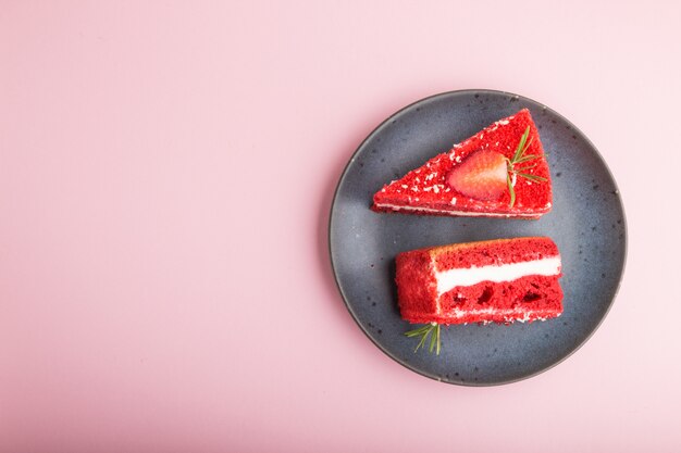 Homemade red velvet cake with milk cream and strawberry on blue ceramic plate isolated on a pink pastel background. top view, copy space.