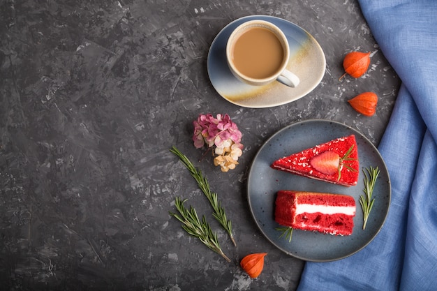 Homemade red velvet cake with milk cream and strawberry  with cup of coffee on a black concrete background. top view, copy space.