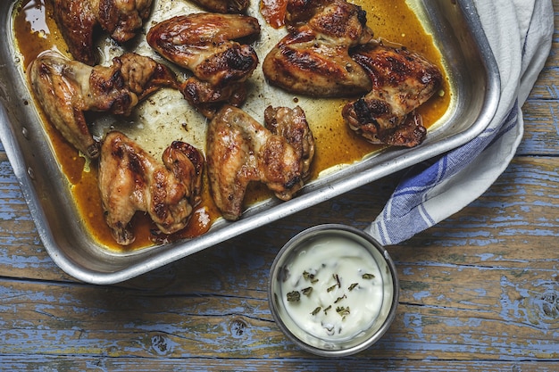 Homemade Roasted chicken wings in baking tray on wooden table