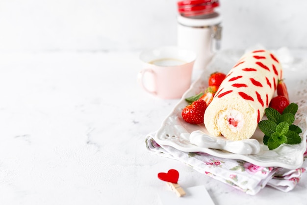 Homemade roll with strawberries cream and mint leaves Dessert on a white stone background Selective focus